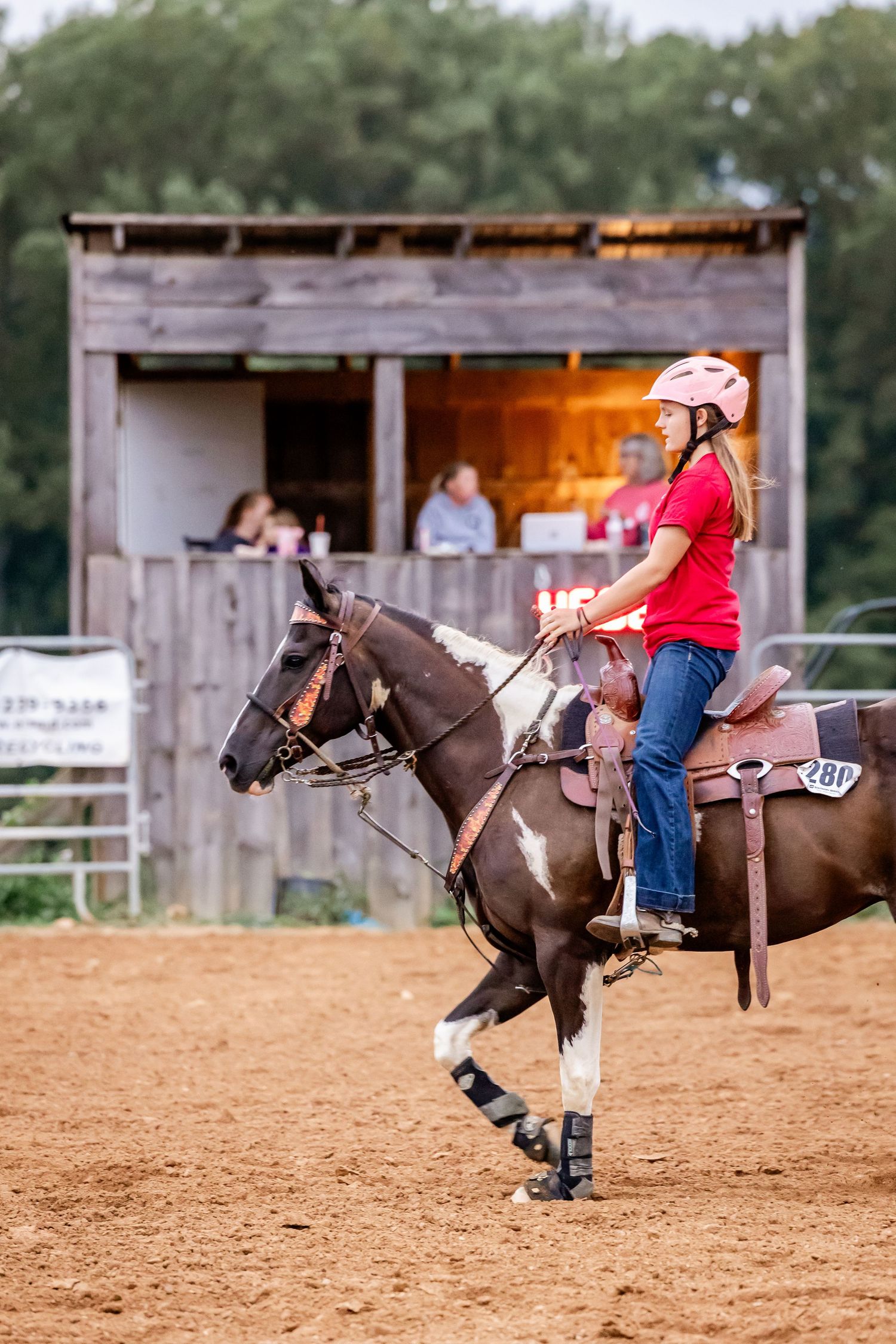 Horse performing controlled slide maneuver in sandy arena during competition.