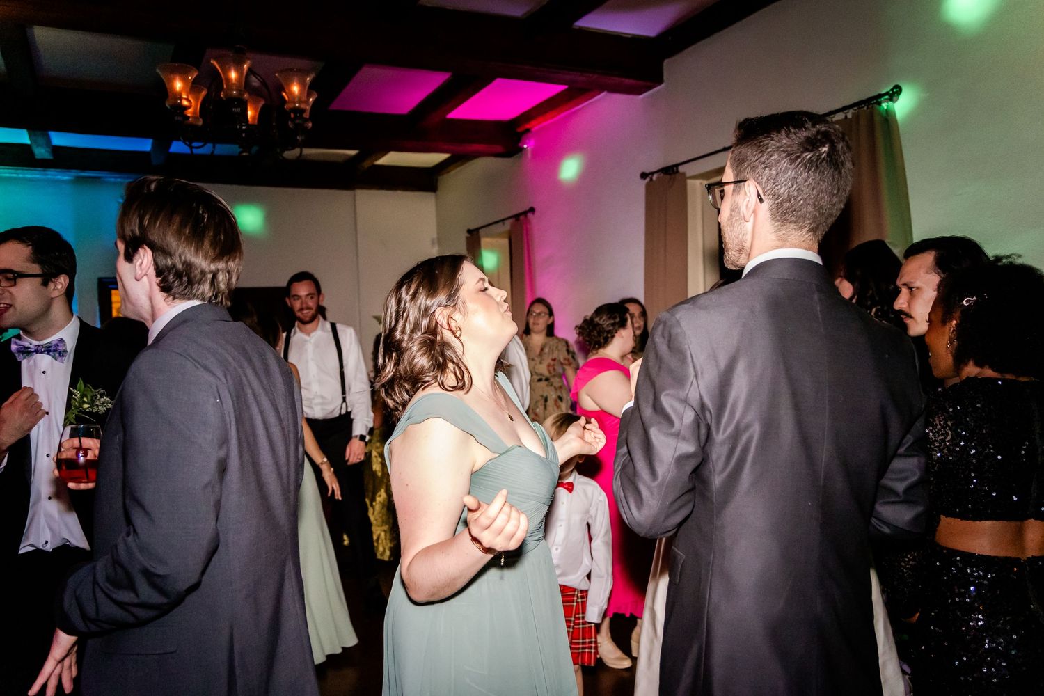 Wedding reception dance floor with colorful lighting and guests enjoying the celebration.