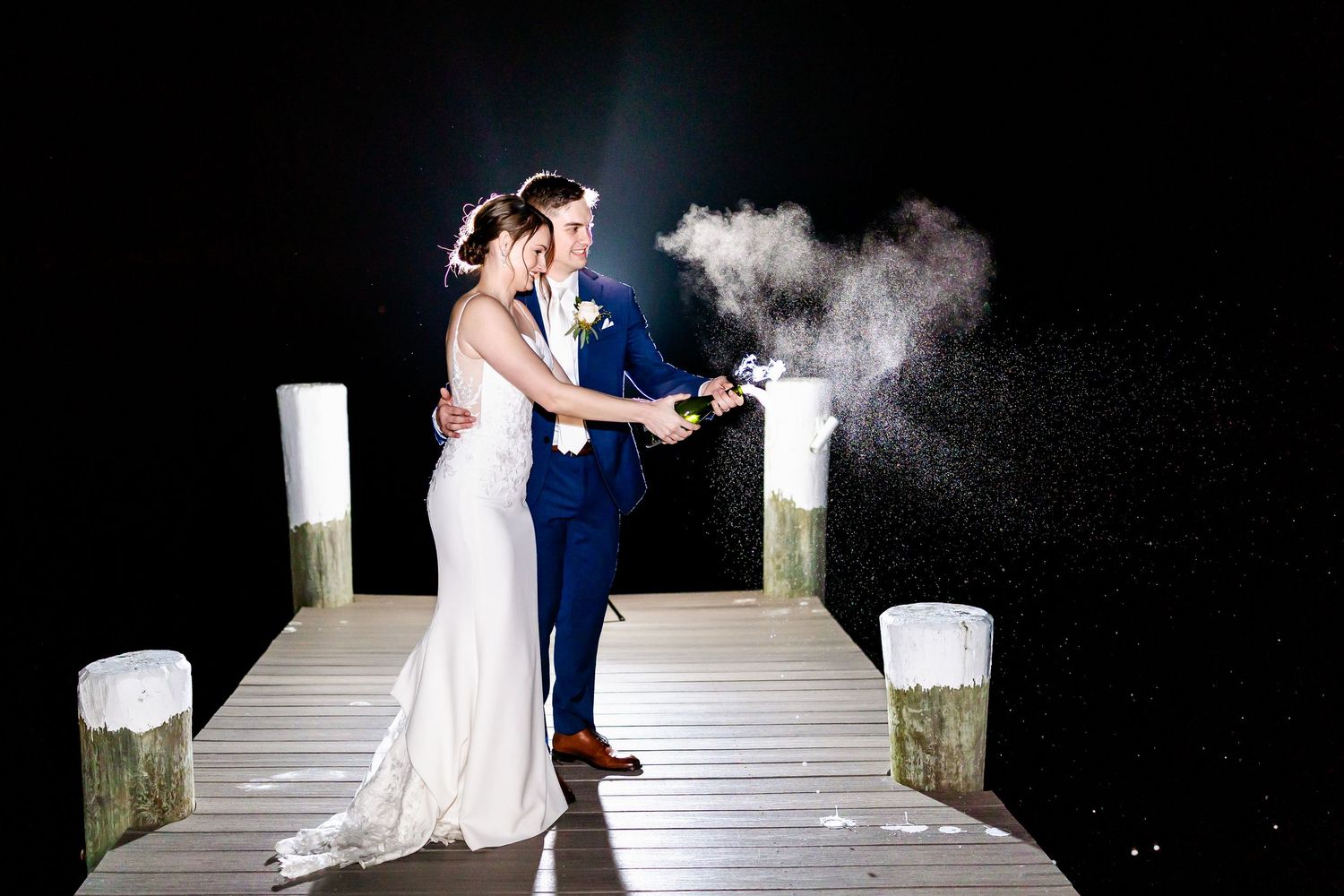 Couple sharing romantic dance moment on wooden dock at night with atmospheric lighting.