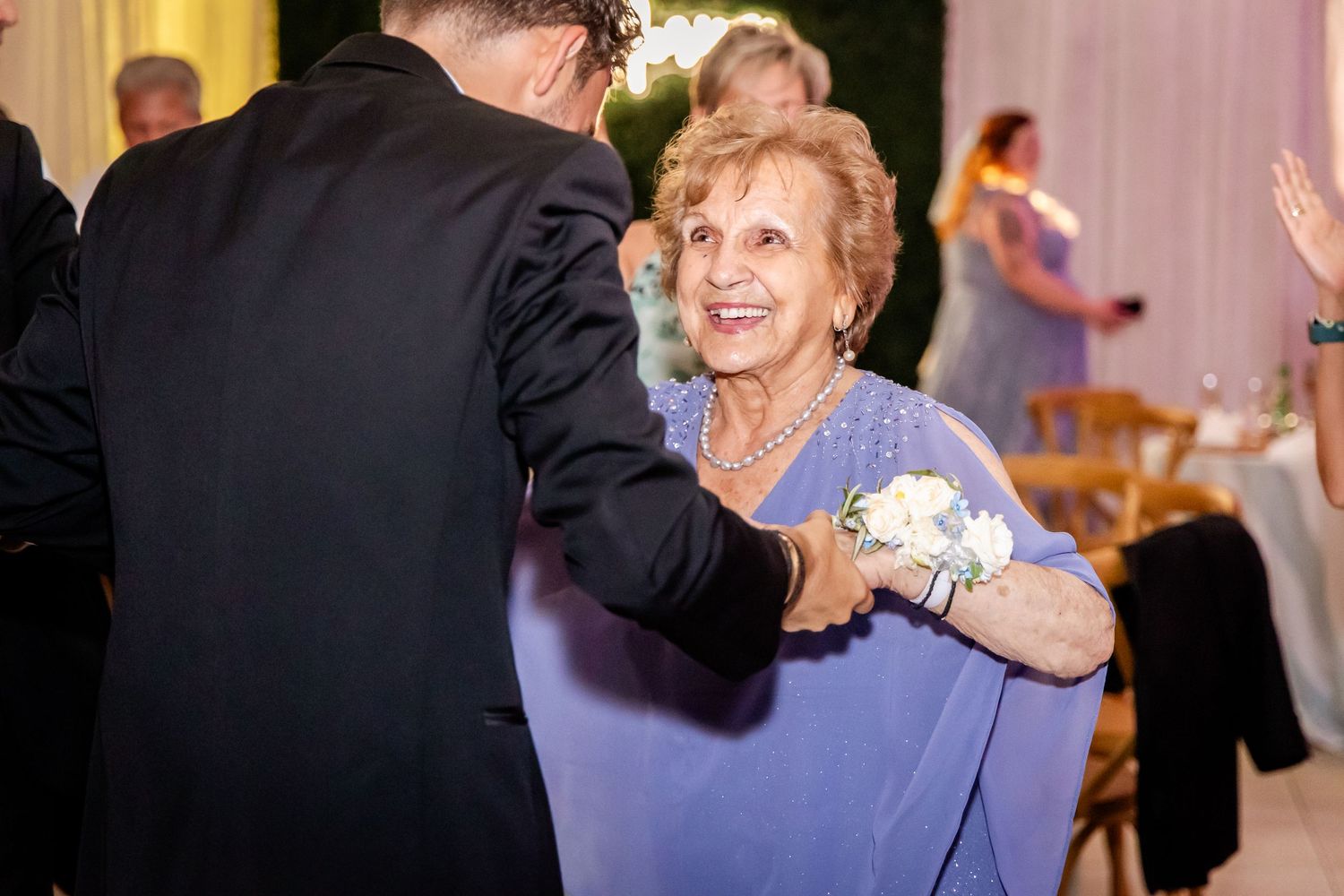 Wedding guests dancing and celebrating on a festively lit dance floor at an evening reception.