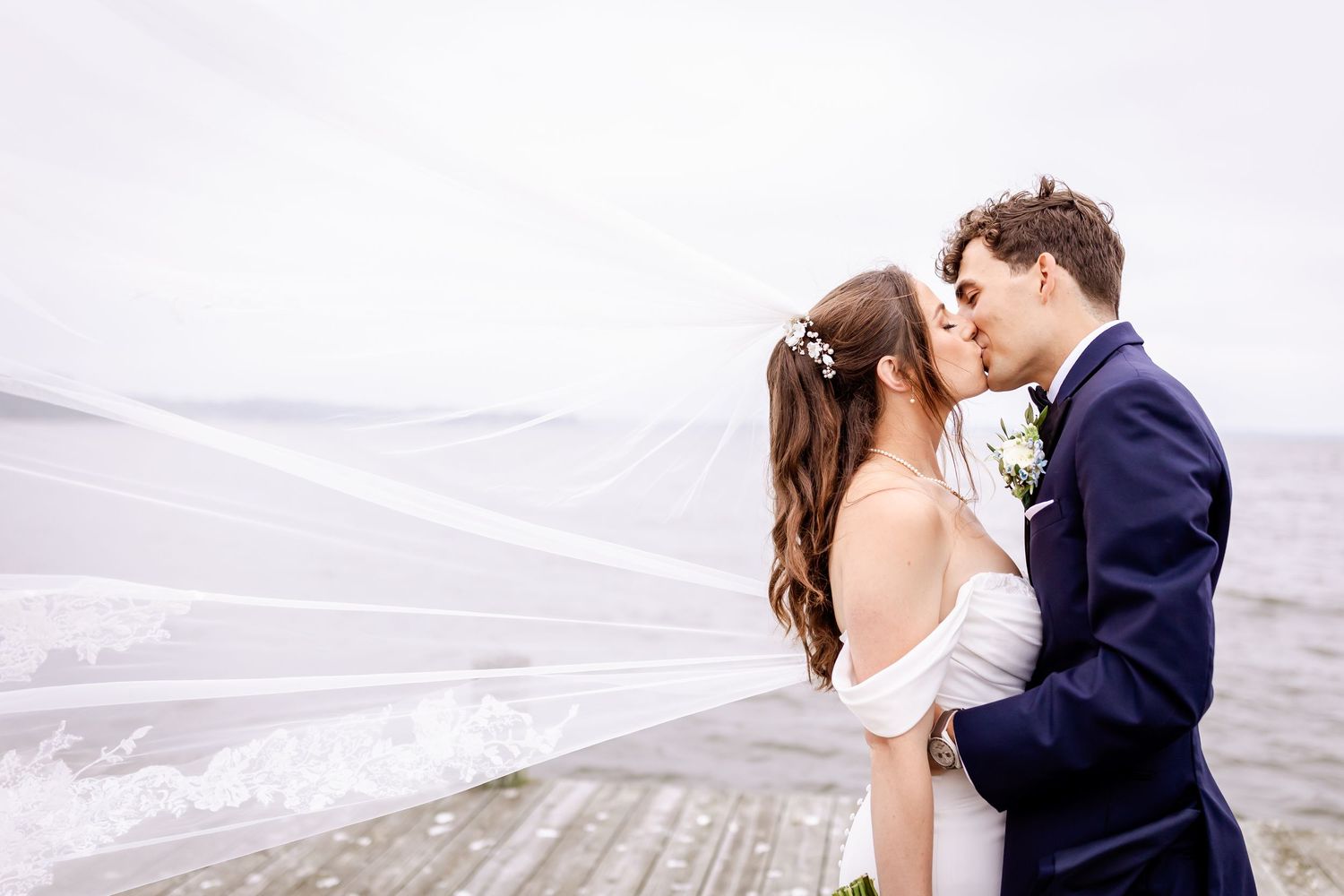 A couple shares an intimate moment on a scenic beach during their wedding photoshoot.