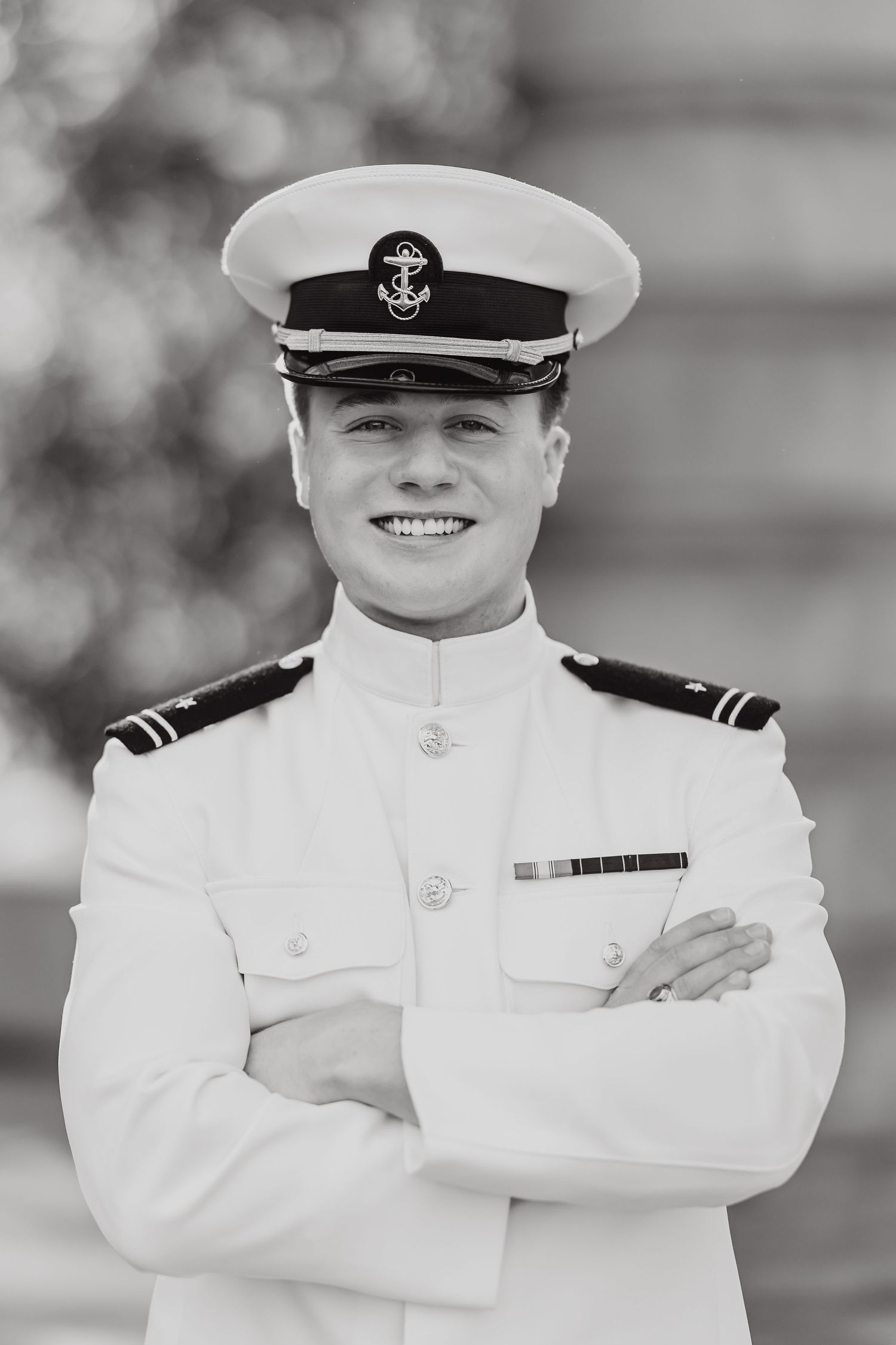 Black and white portrait of naval officer in dress whites with service cap.