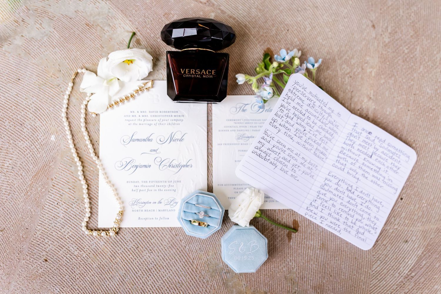 Wedding stationery flatlay with handwritten cards, blue details, and white floral accents.