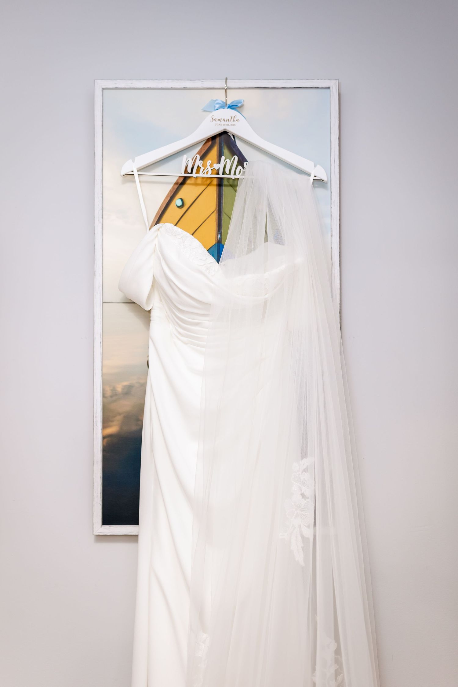 White wedding dress hanging on display against grey wall.