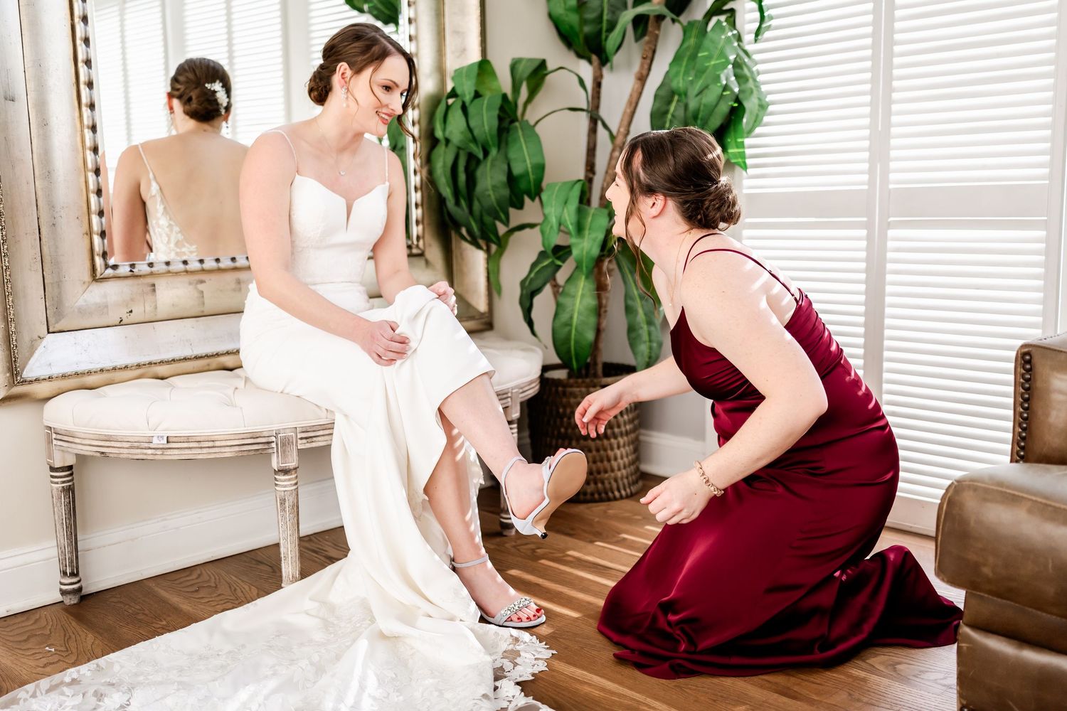 Bridal preparation moment in elegant room with large mirror and indoor plants.