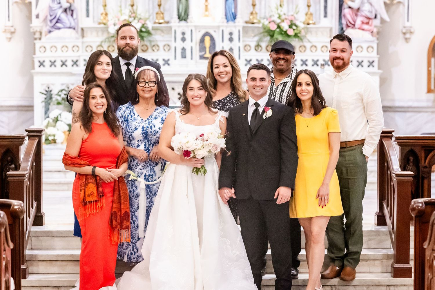 Wedding party members lined up inside a church with decorative religious artwork and architecture.