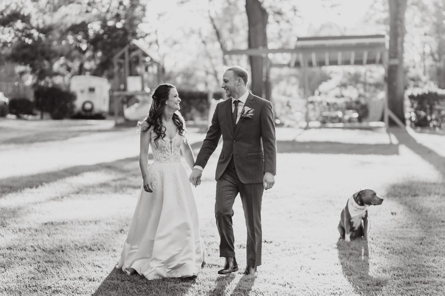 Black and white wedding portraits showing couple walking together on tree-lined path.