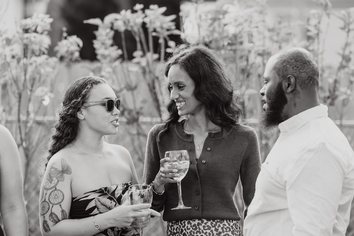 Black and white photo of wedding guests enjoying drinks and conversation at reception.