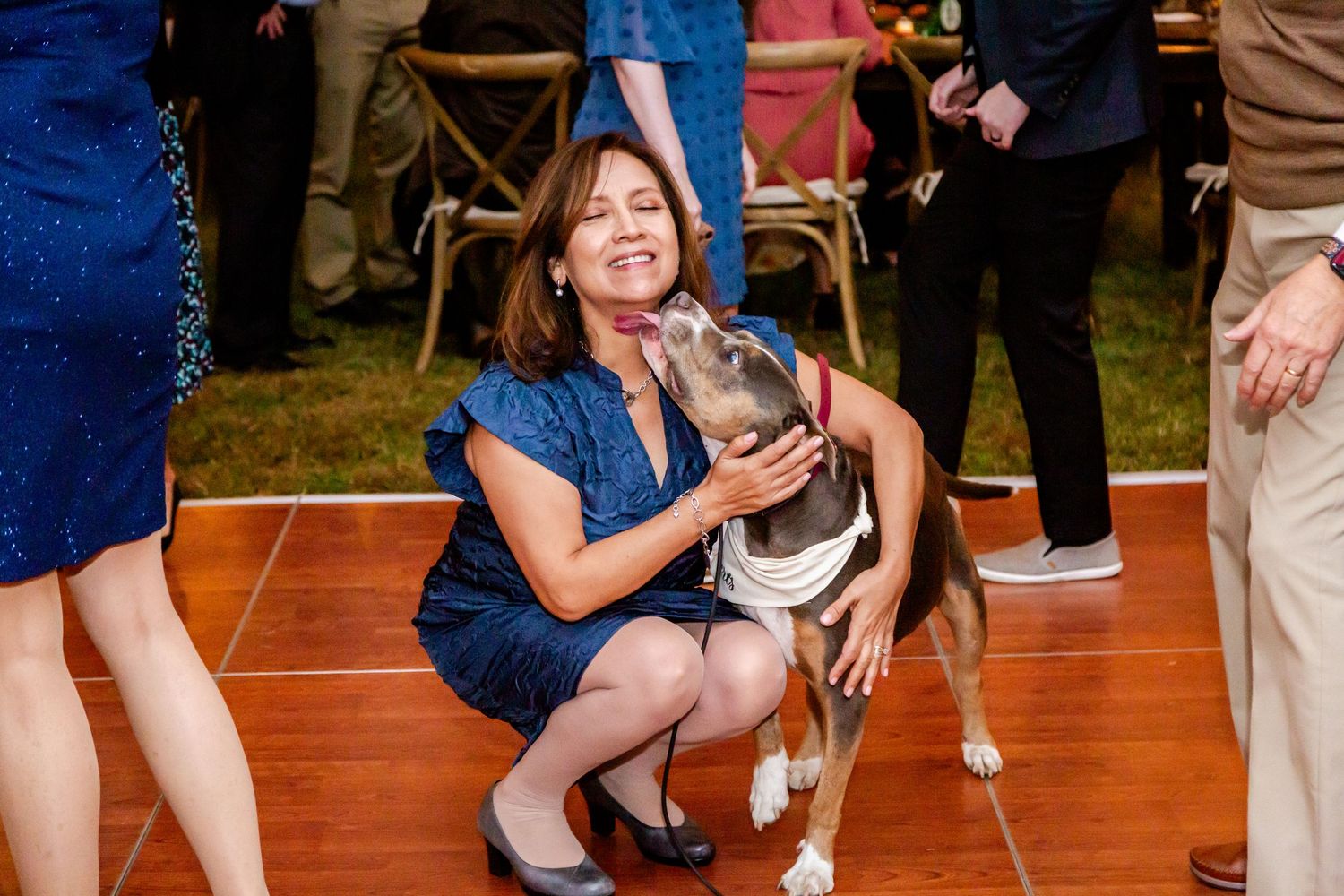 Wedding guests dancing and celebrating together on a wooden dance floor at an evening reception.