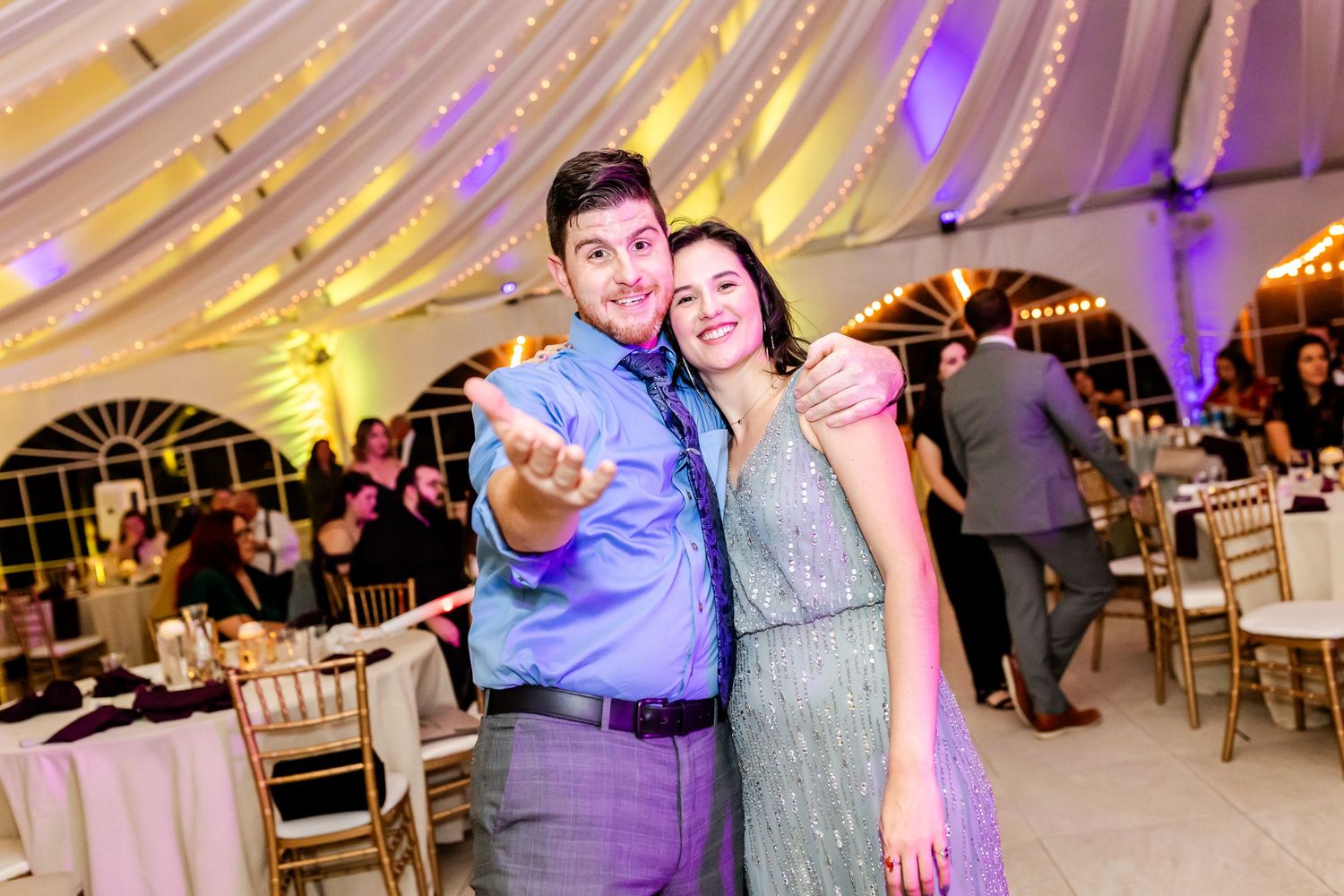 A dancing couple pose together under golden draped fabric ceiling at an elegant wedding reception.