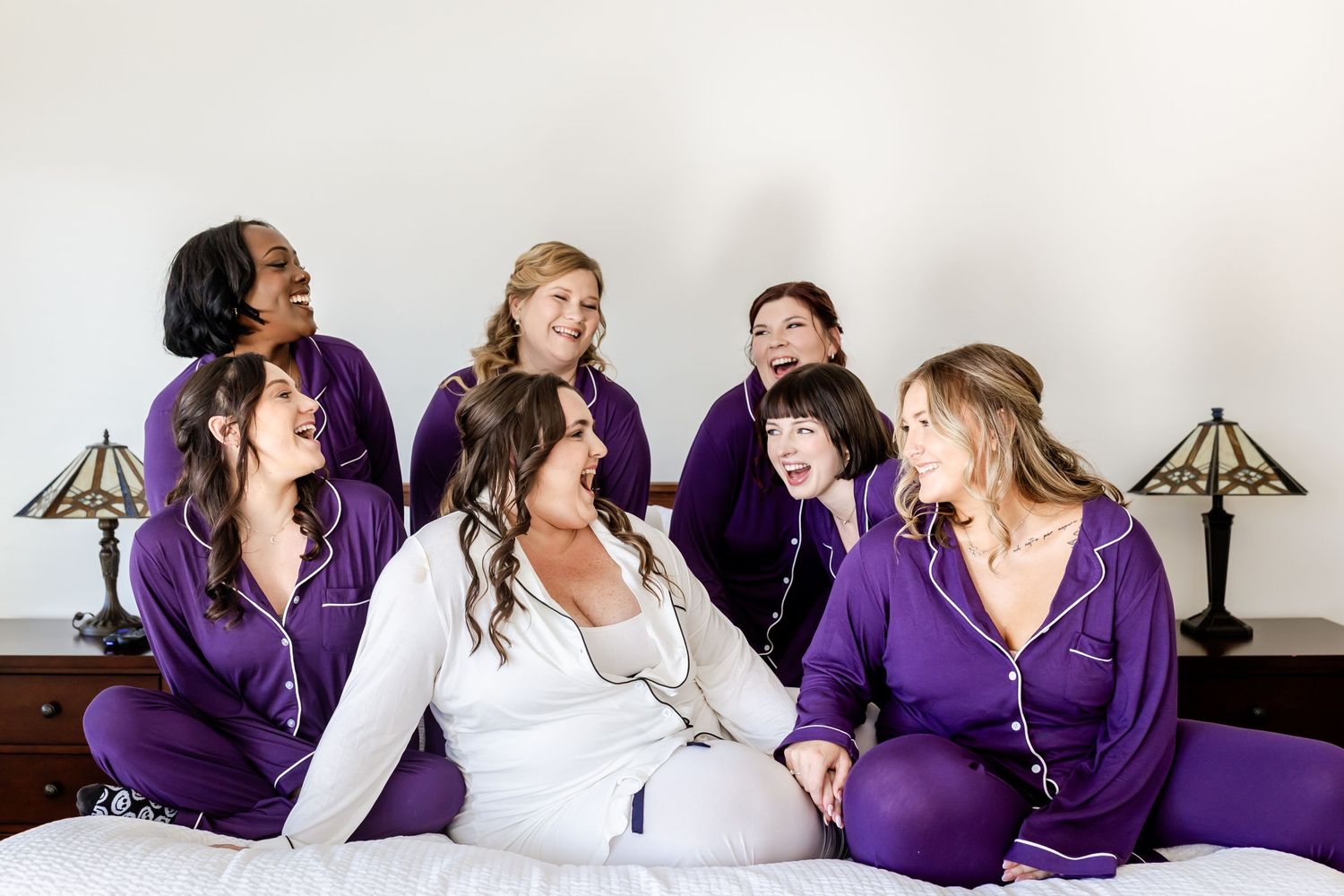Wedding party in matching purple robes relaxing together during preparation.
