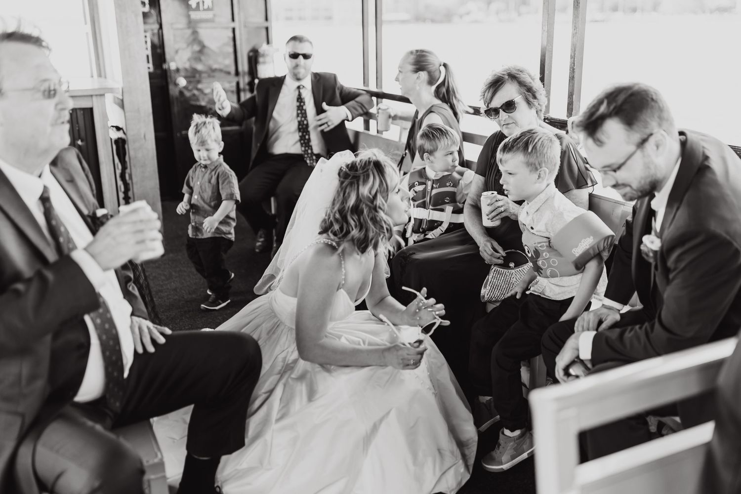 A black and white photo of wedding guests gathered on a boat for a celebration.