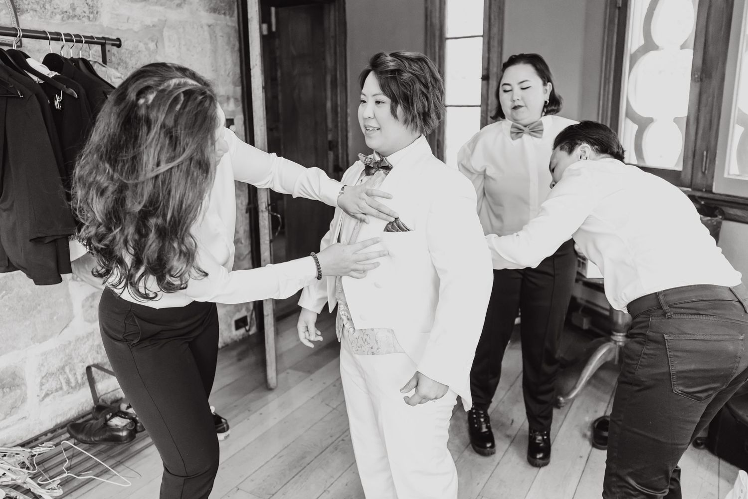 Four people engage in wedding day preparations while getting dressed.
