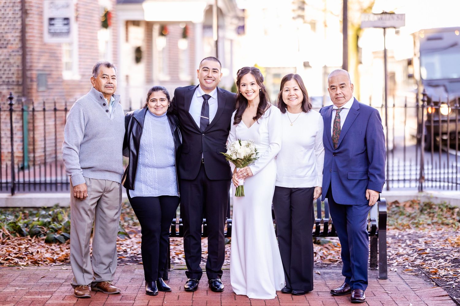 Wedding party photo showing a bride and groom with extended family on a fall day.