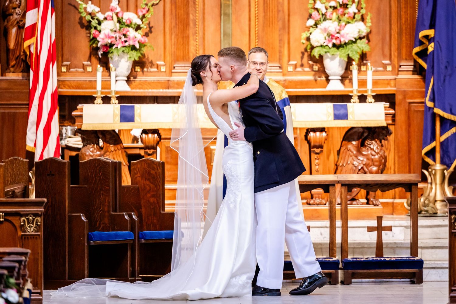 Church wedding ceremony with American flags and floral arrangements decorating wooden interior.