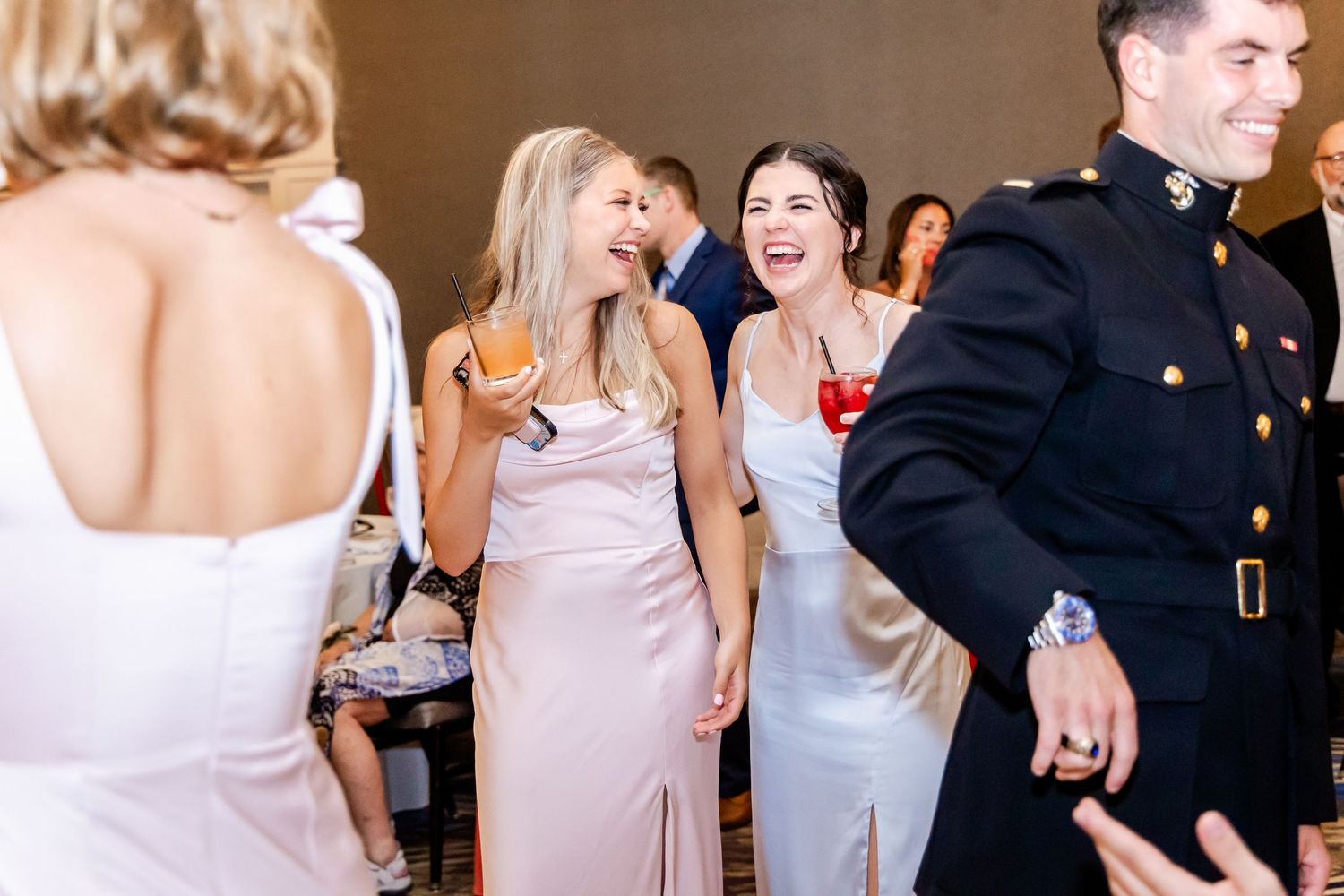 Wedding party members dancing and socializing during an indoor reception celebration.