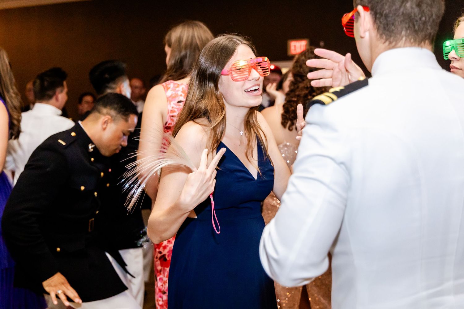 Party guests dancing and celebrating with fun props at an elegant indoor event.