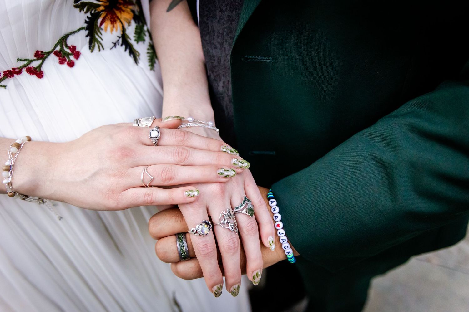 Close-up view of hands displaying wedding rings with romantic autumn leaves in the background.