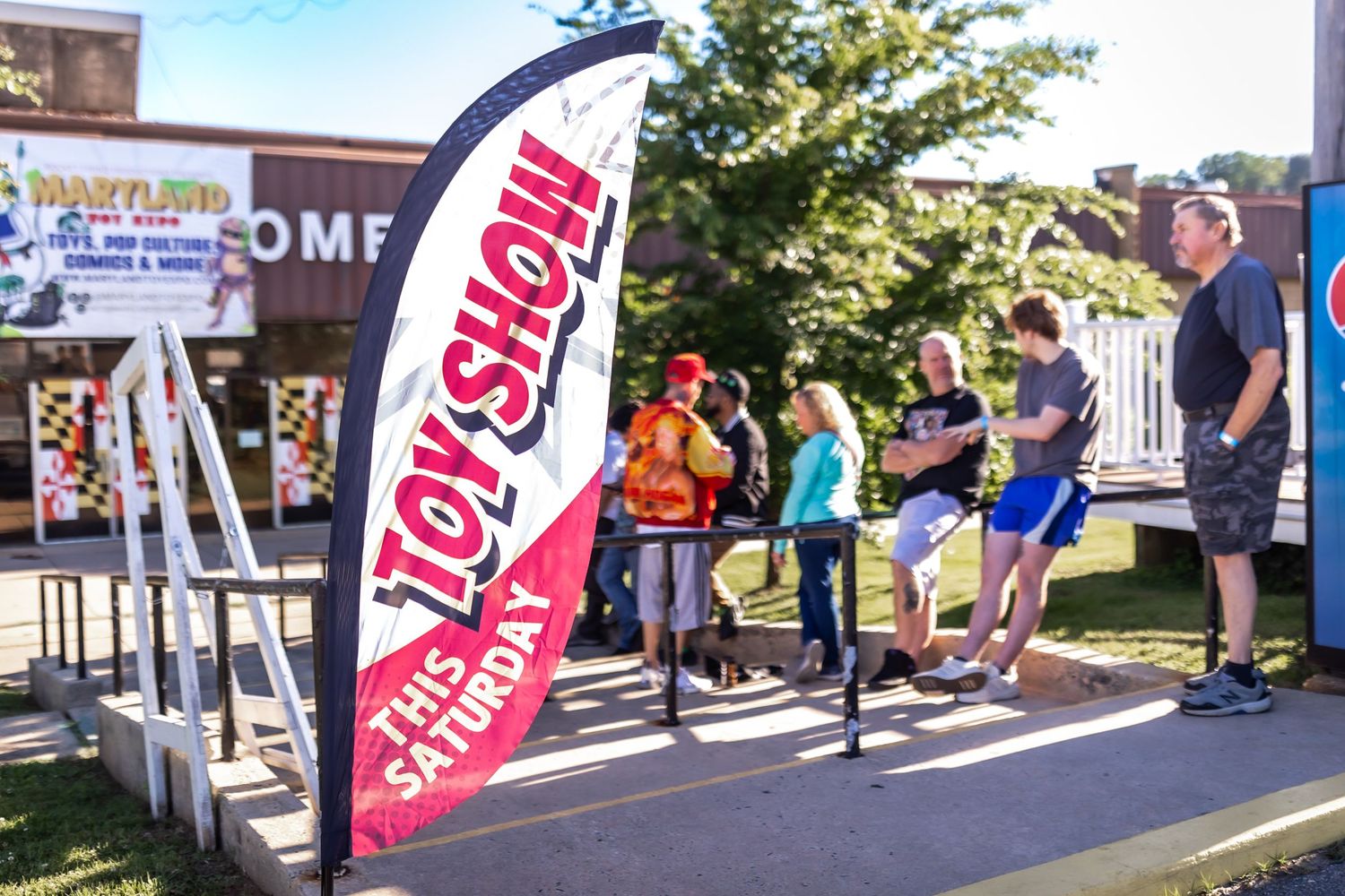 Outdoor event with promotional banners and tents set up along a walkway.