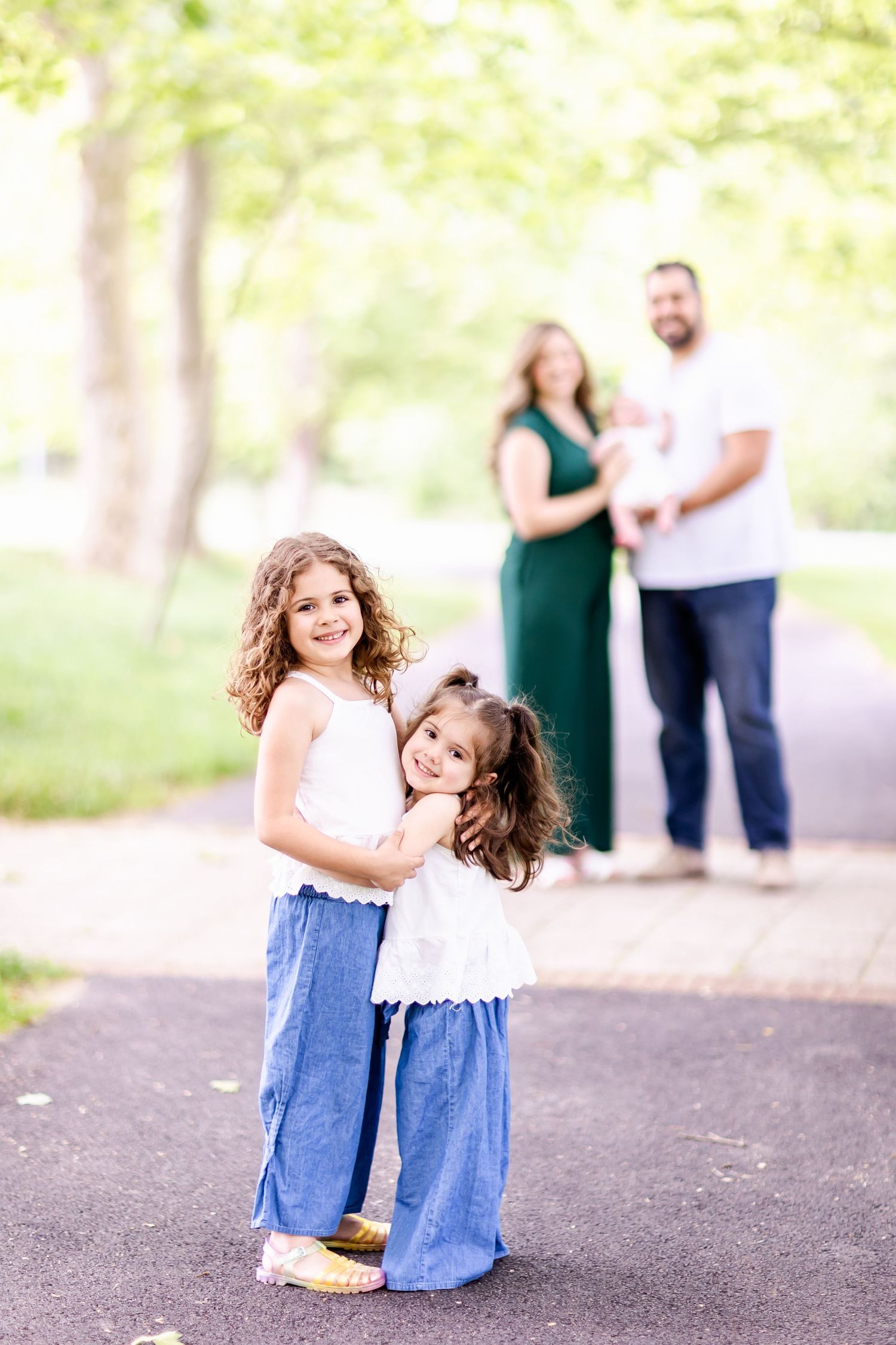 Joyful outdoor portrait session on paved path with greenery in background.