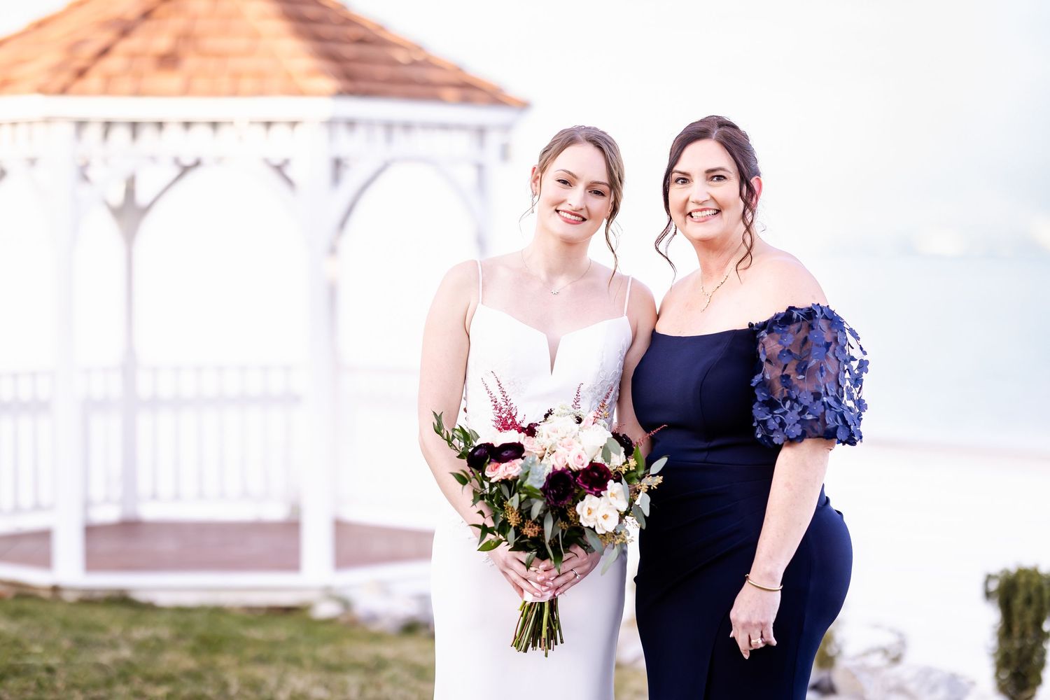 Outdoor wedding portrait with white gazebo in background during daytime.