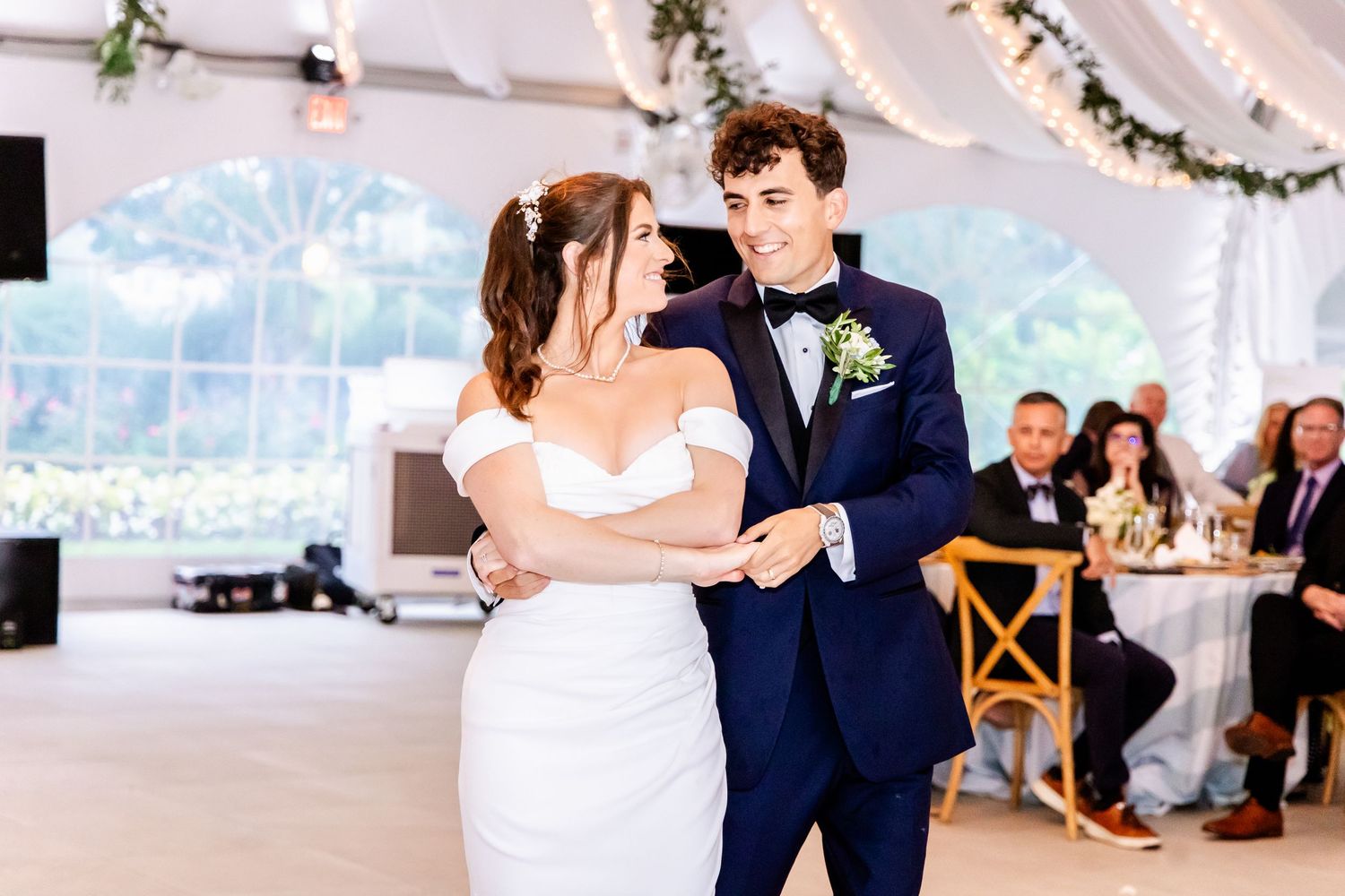 Wedding reception dance floor with couples dancing under white tent.