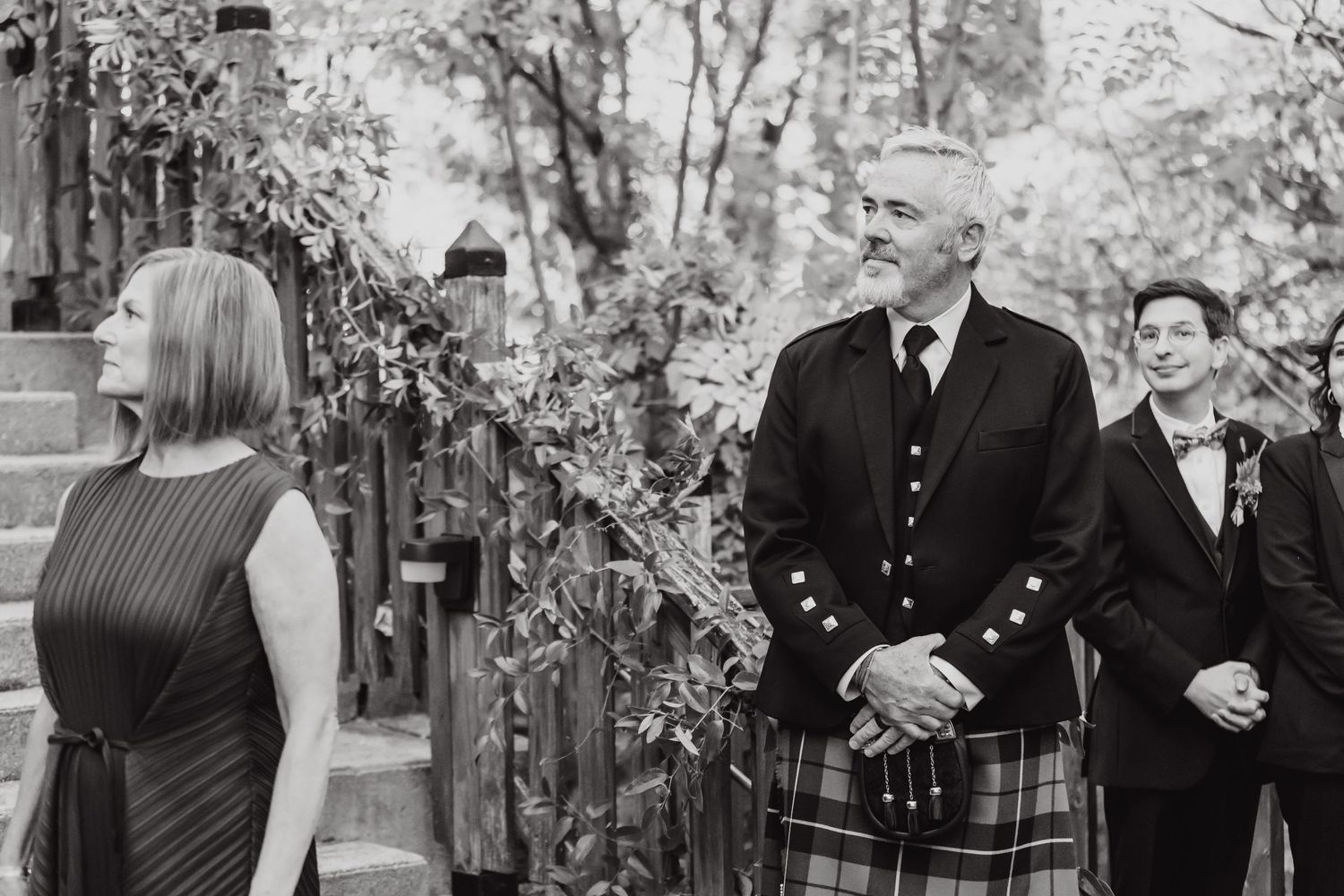 Wedding ceremony at stone church entrance with groom in traditional Scottish kilt.