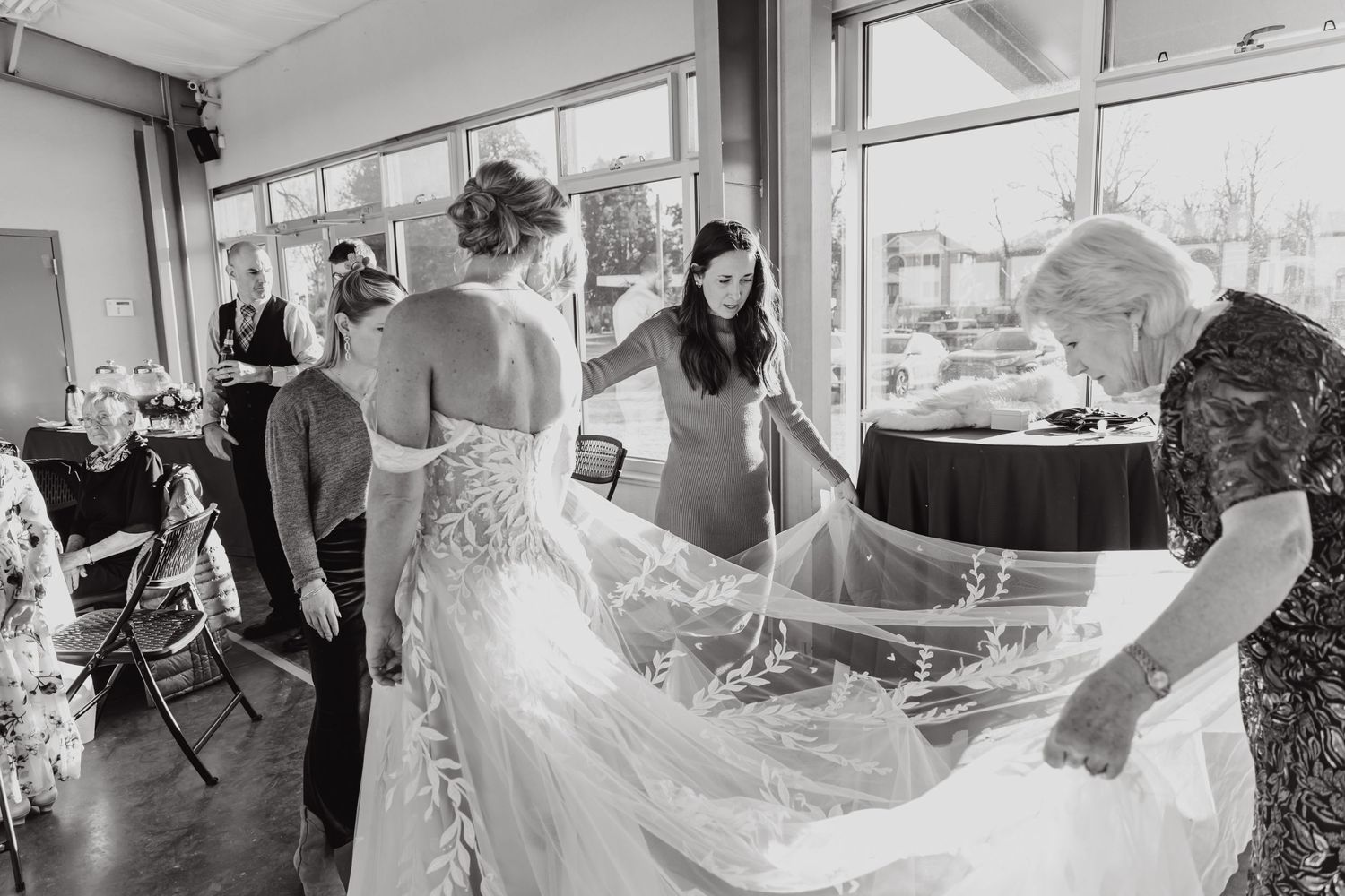 Wedding preparations showing attendants helping with a flowing bridal gown veil.