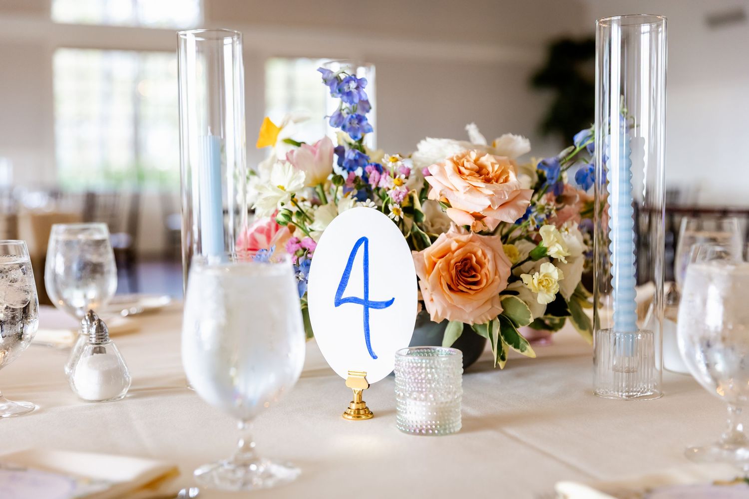 An elegant wedding table setting with table number 4, floral centerpiece and glass stemware.