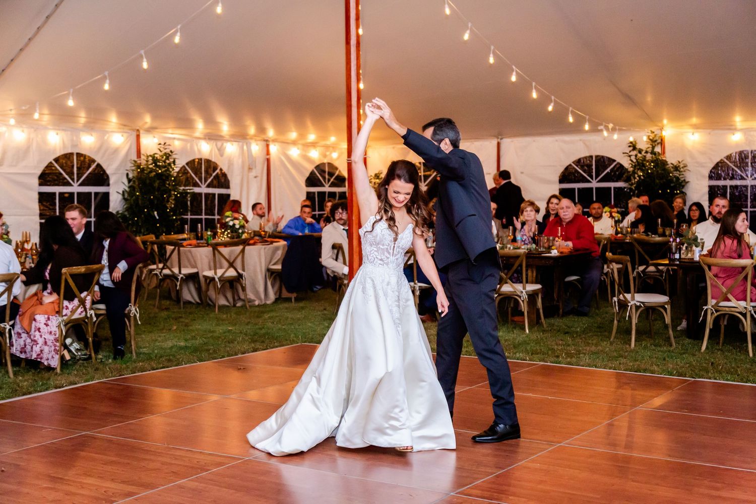 Wedding reception dance floor under a tent with string lights creating a warm ambiance.