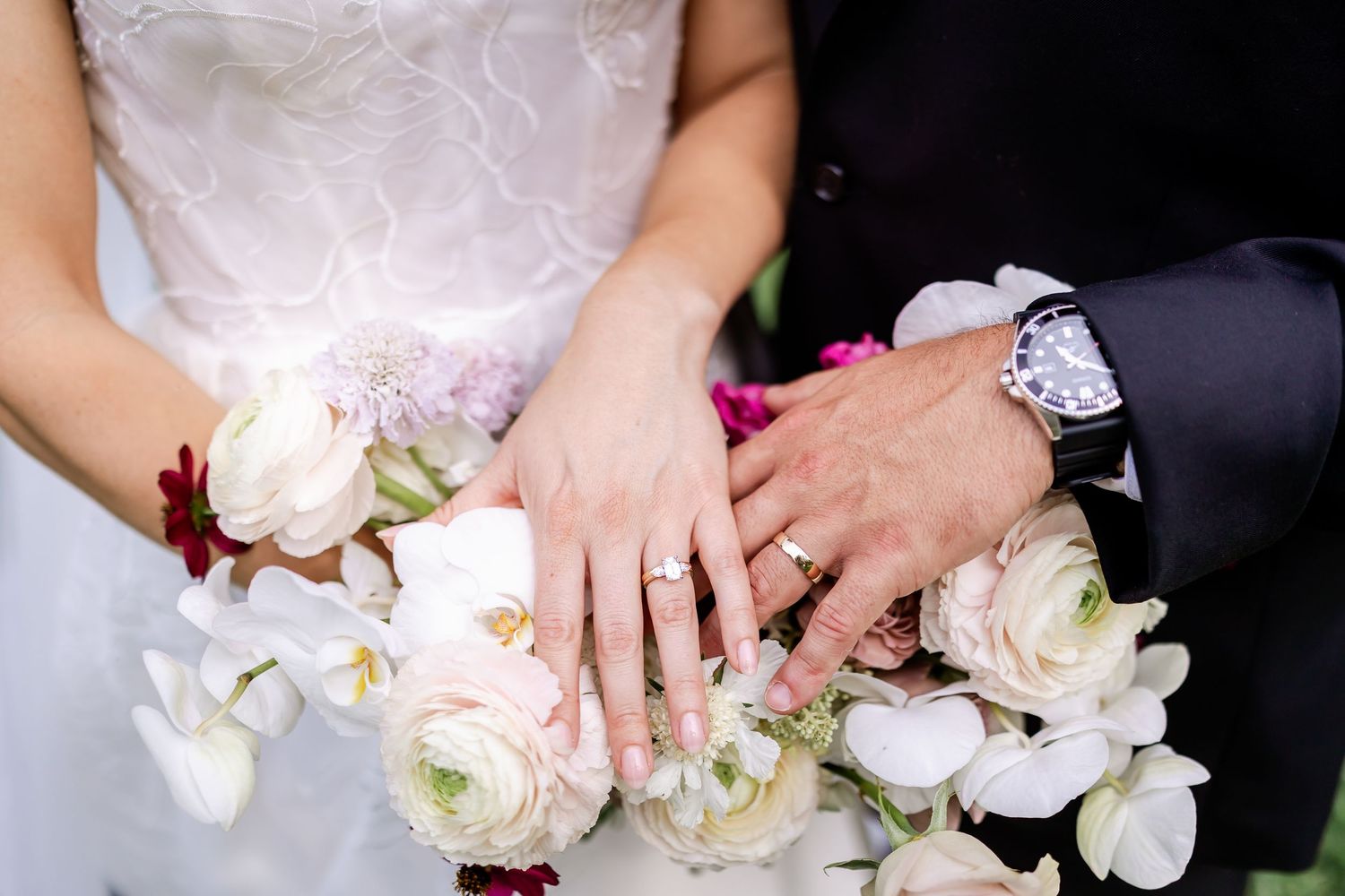 Close-up of bridal bouquet with white orchids and roses against wedding dress details.