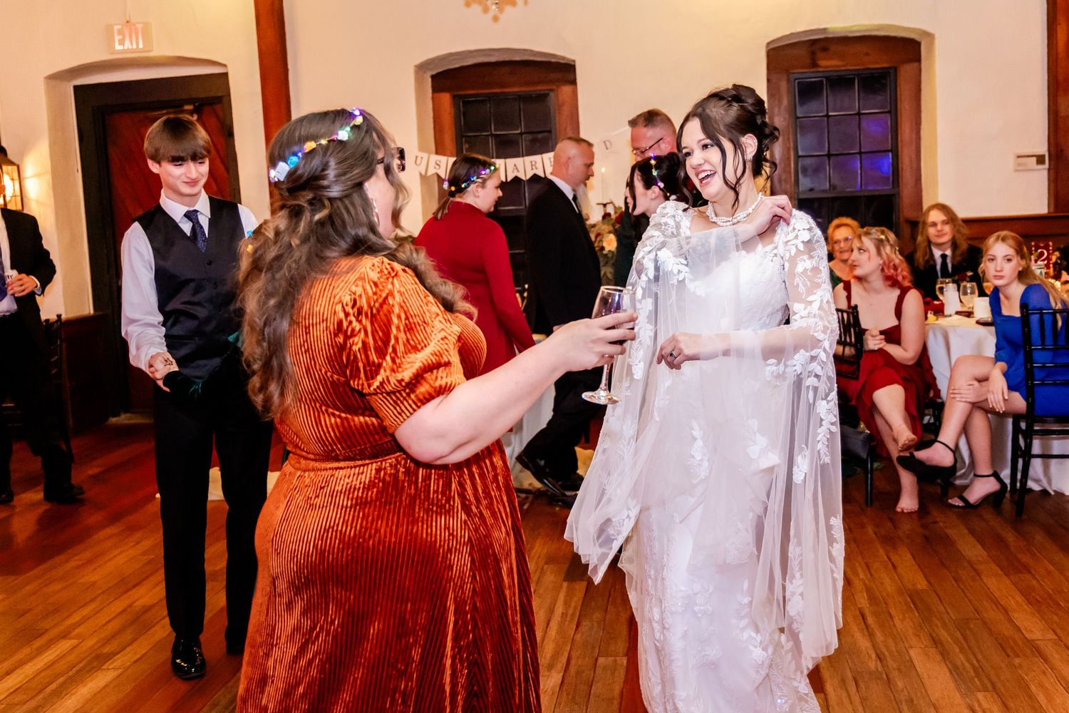 Wedding celebration with guests dancing and socializing on wooden dance floor.