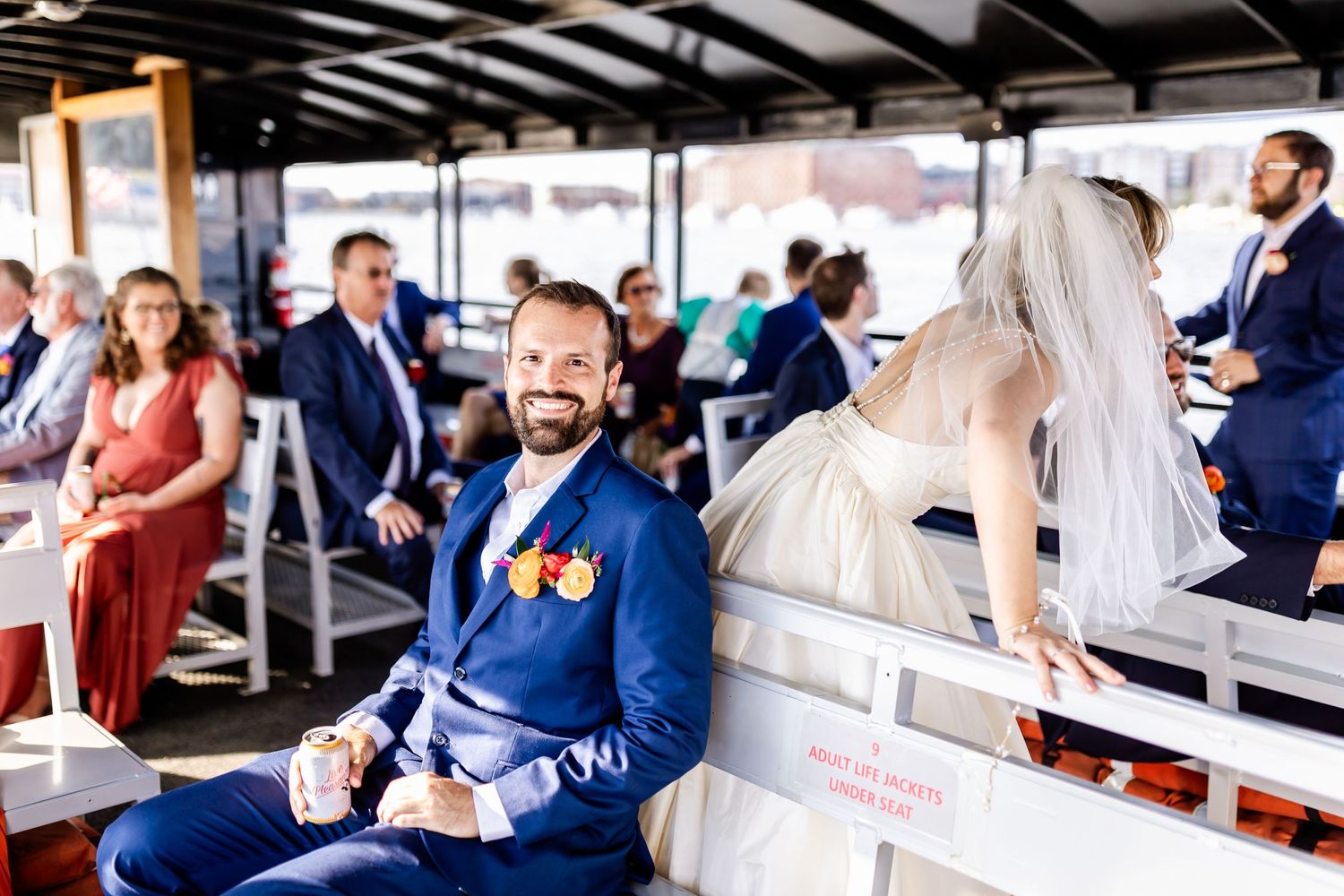 Wedding guests seated on a covered boat deck for a nautical ceremony.