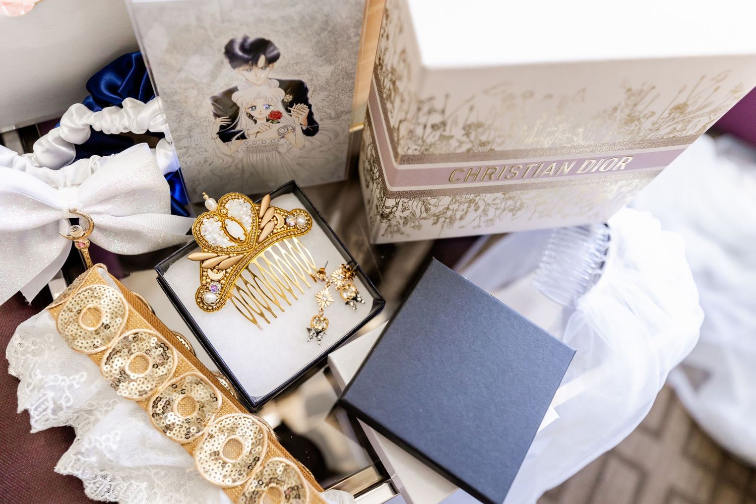 Wedding accessories including decorative gold hair combs and gift boxes arranged on white fabric.