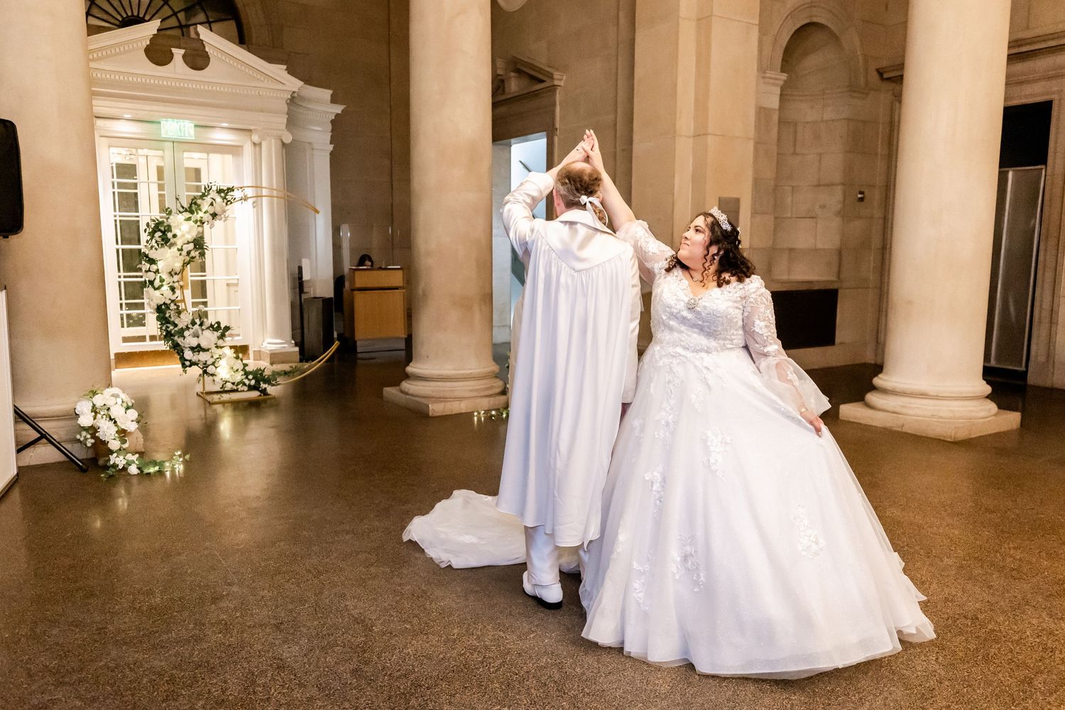 Playful wedding portrait in an elegant columned venue.