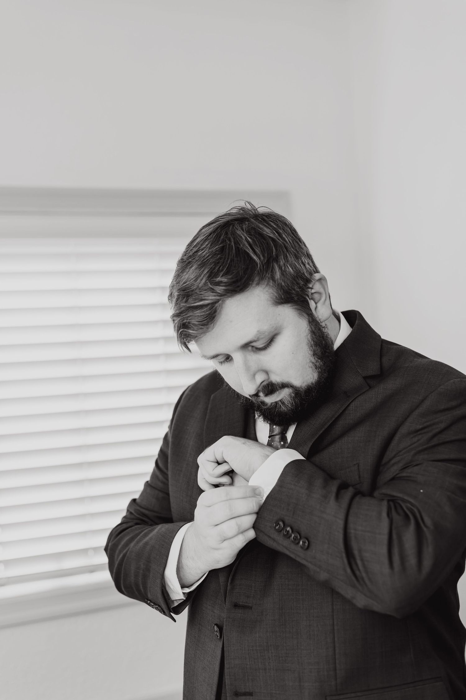 Person adjusting cufflink while getting dressed in formal attire.