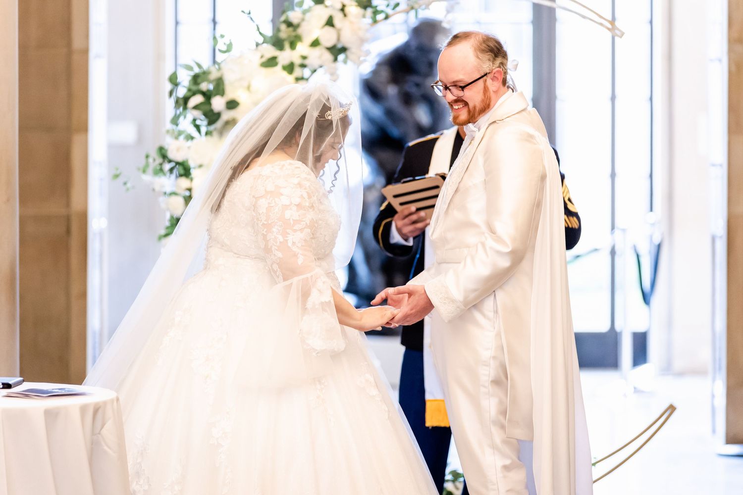 Wedding ceremony in progress with couple and officiant in white robes at the altar.