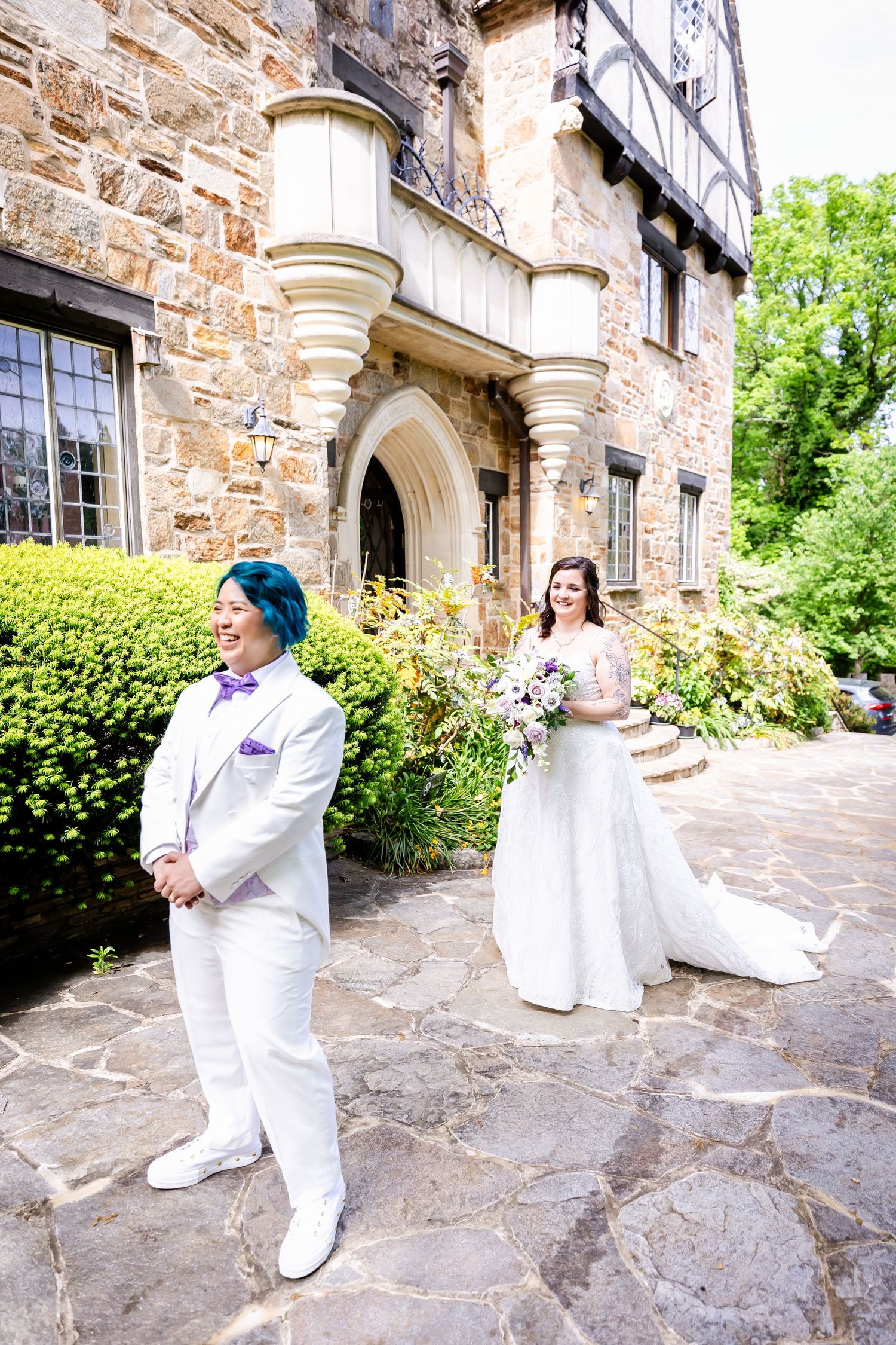 A first look photo in front of a stone castle with a couple in white attire.