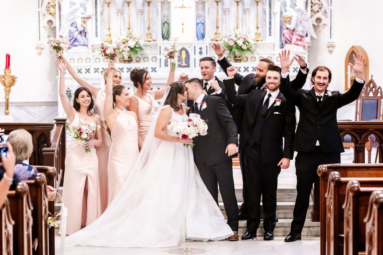Wedding party celebrating in an elegant church ceremony with traditional decor and floral arrangements.