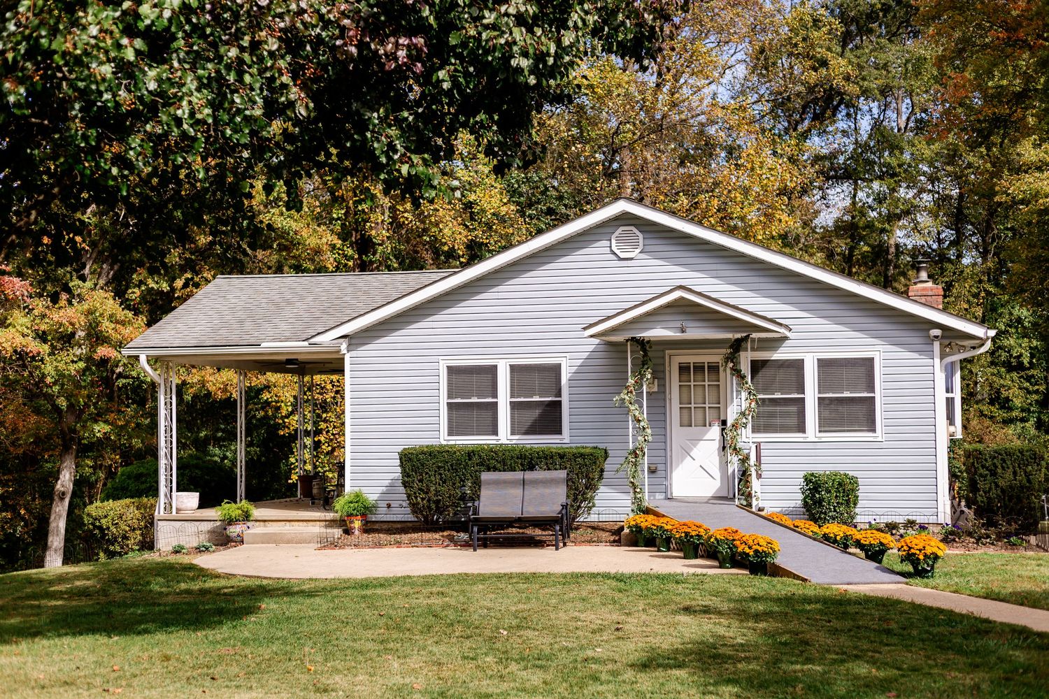 Long white ranch-style house with landscaping and trees in the yard.