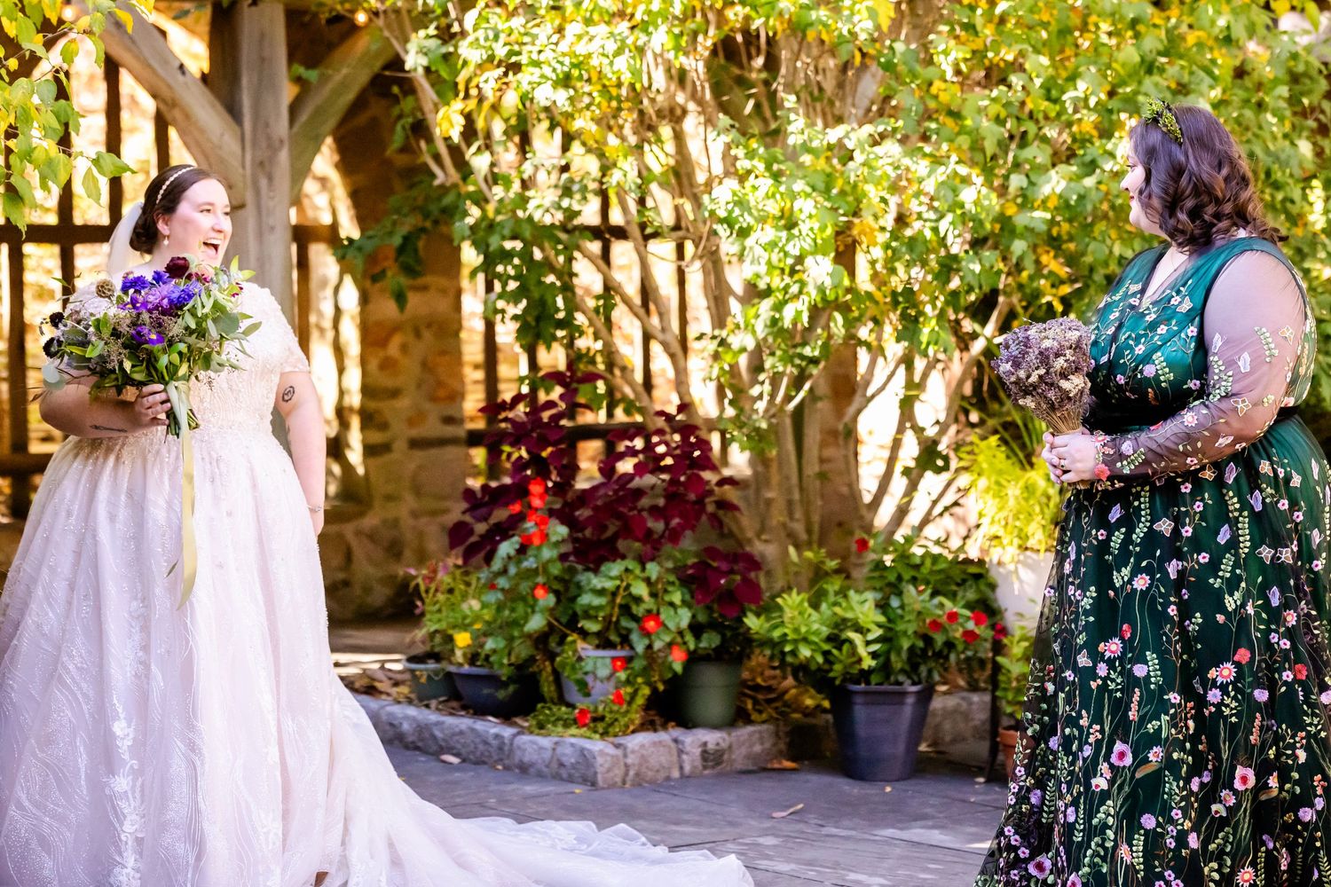 Wedding party members in white and floral dresses posing in garden setting.