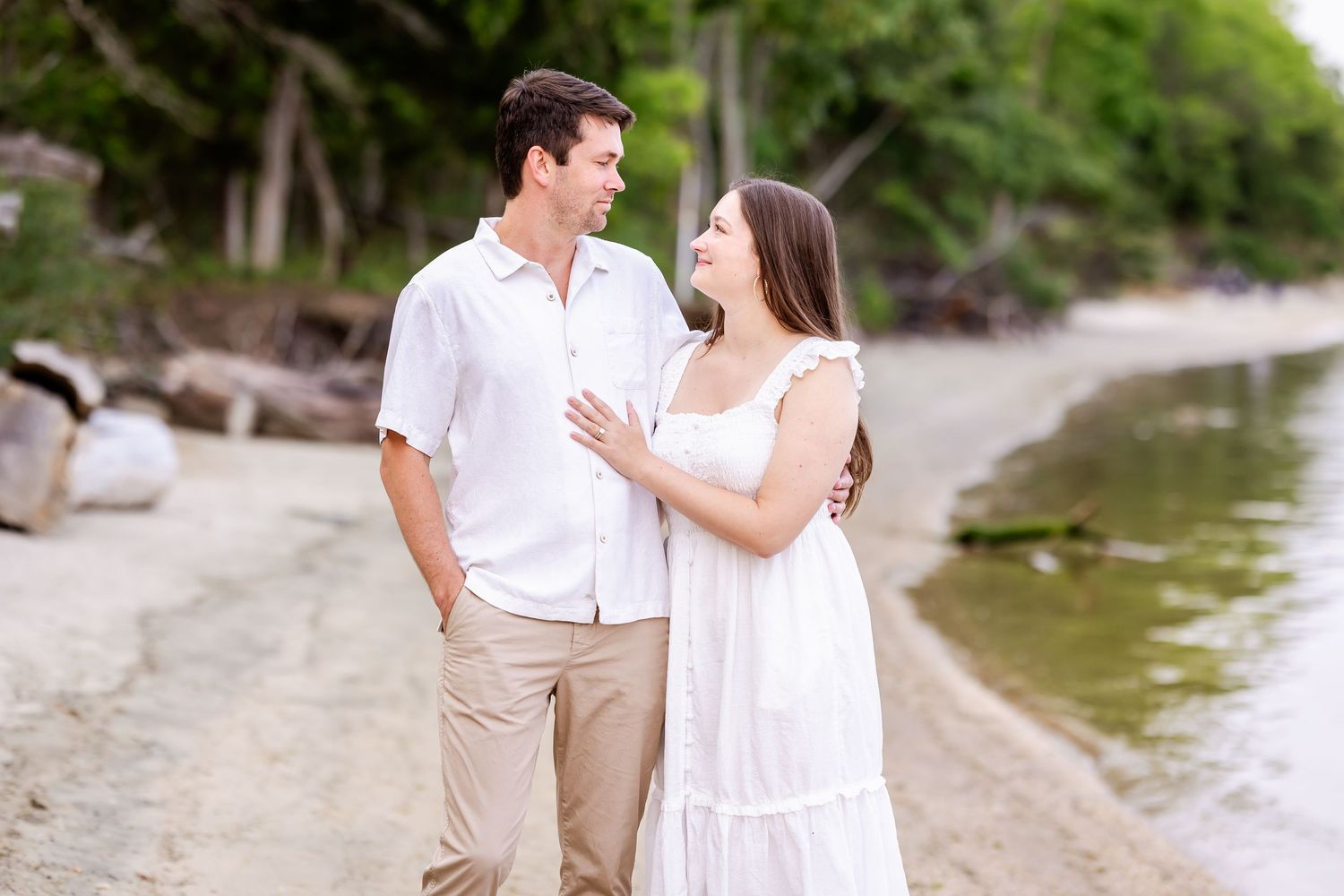 Couple in beachwear walking together and embracing on a tropical shoreline at sunset.
