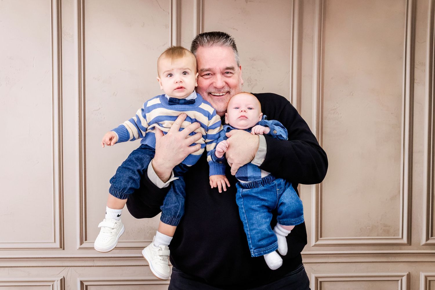 Family members interact playfully with children during indoor studio photoshoot.