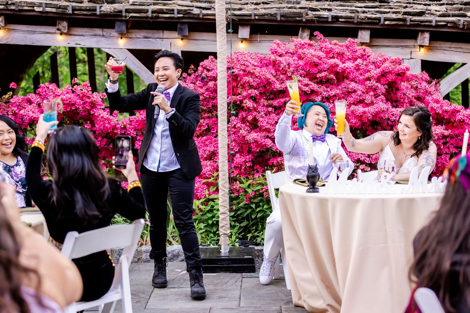 An intimate moment between couple during wedding reception with bright pink azaleas in background.