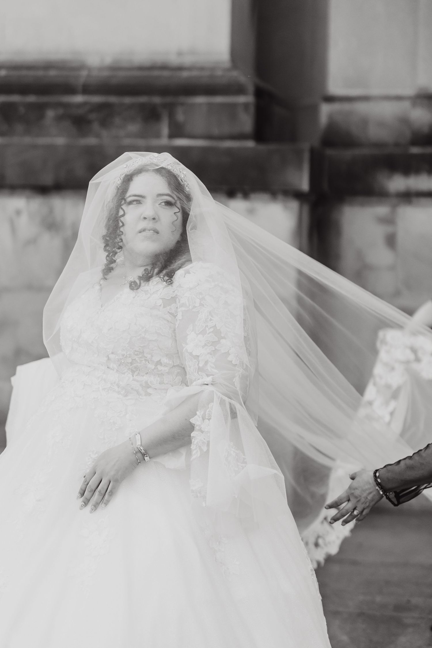Artistic black and white bridal portrait showcasing flowing veil and lace details.