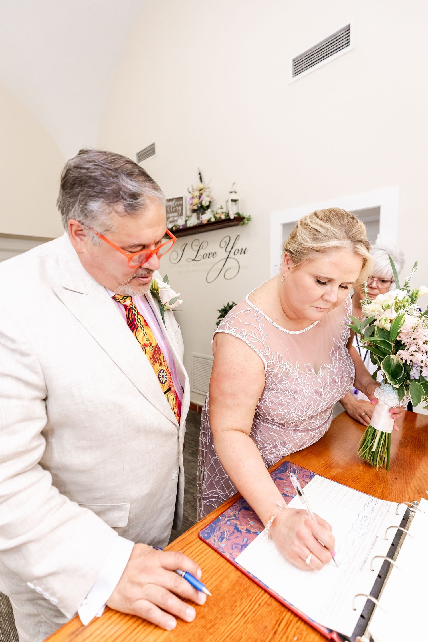 A wedding ceremony in progress with signing of documents on a wooden table.