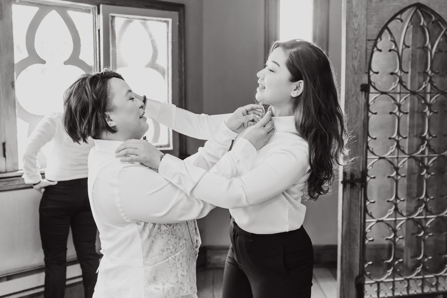 Black and white candid photo of playful moment during wedding preparations.