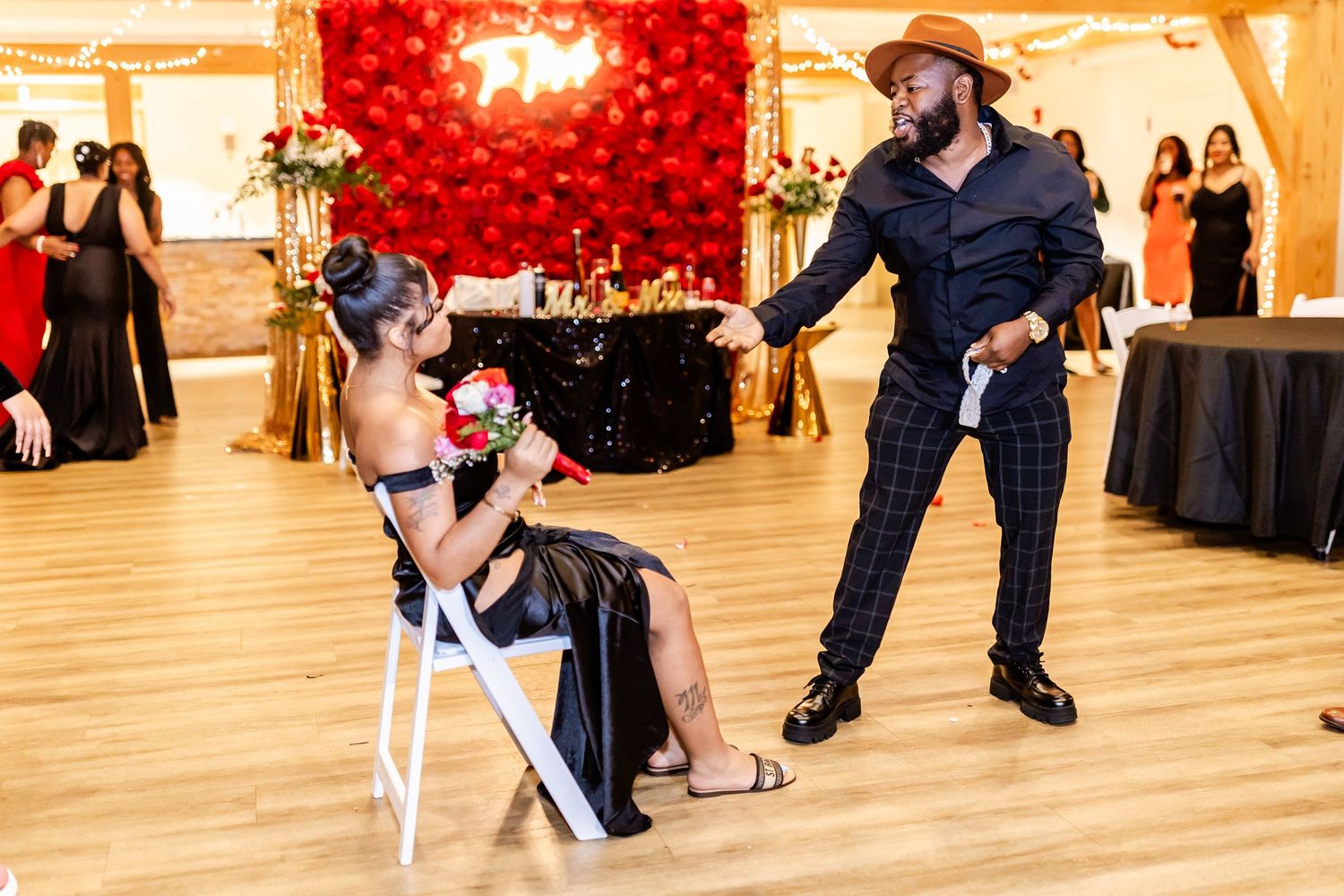 Wedding reception dance scene with red balloon wall and guests in formal attire.