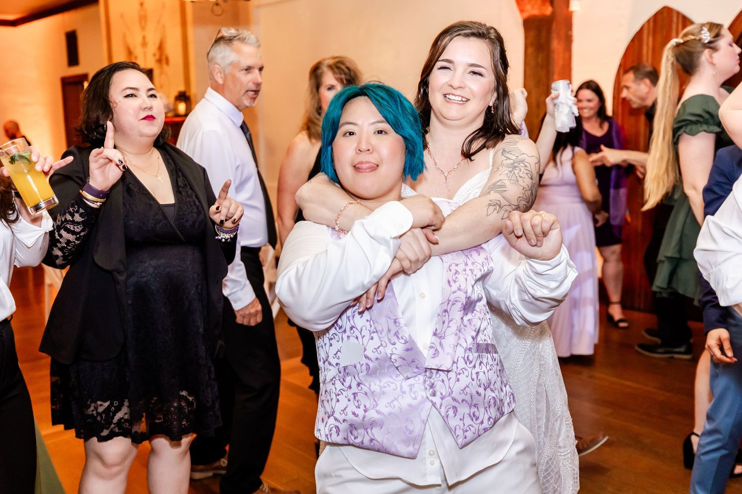 A group of guests dancing and celebrating with joyful expressions at an indoor event.