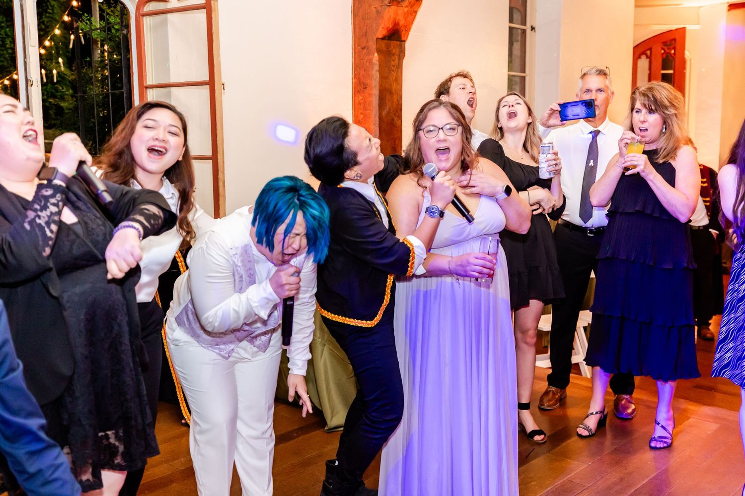 Party guests celebrating with animated expressions and dance moves in an ornate indoor venue.